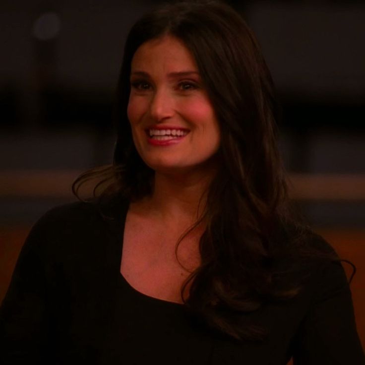 a woman with long dark hair smiles at the camera while wearing a black dress and smiling