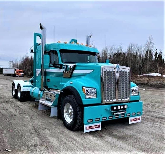 a large blue truck parked on top of a dirt road