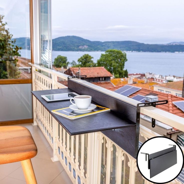 a table with a cup and plate on it in front of a window overlooking the water