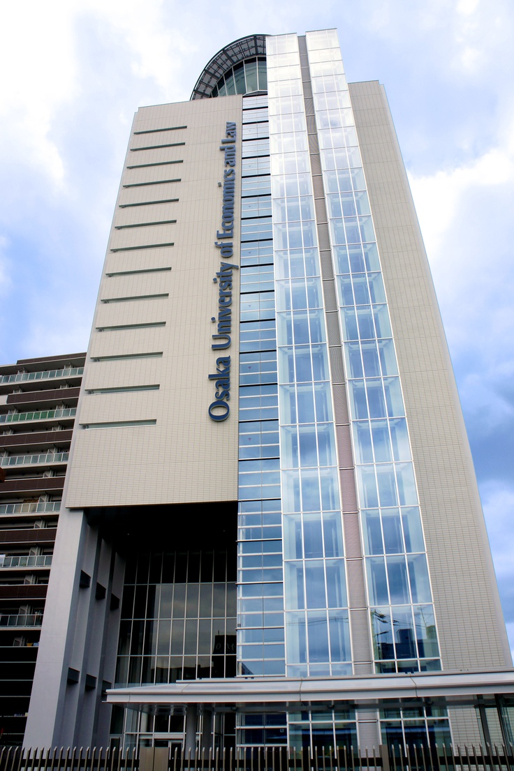 a tall building with a sign on the side of it's face and clouds in the background