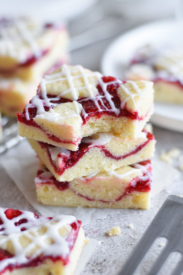 several pieces of cake with white icing and raspberry toppings on top