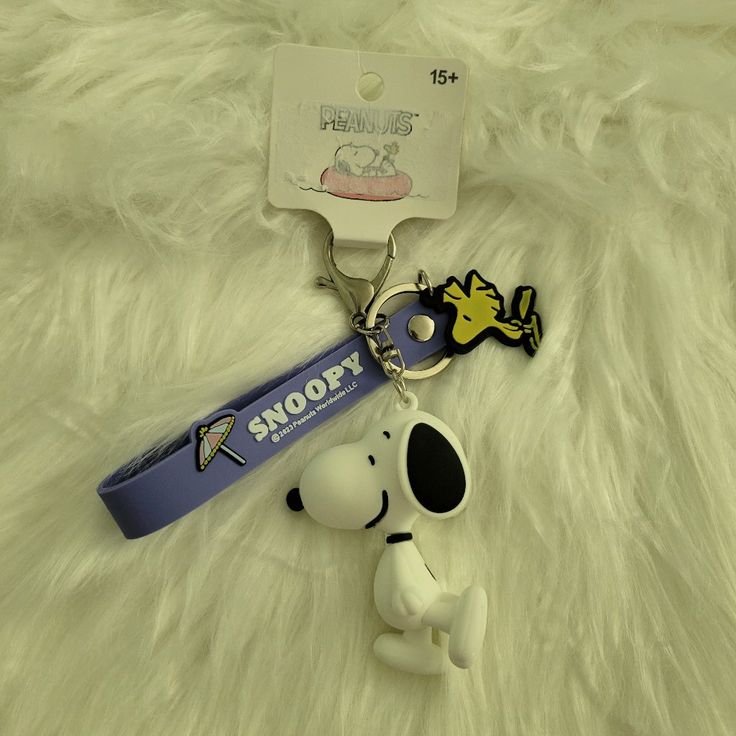 a snoopy keychain is laying on a furry surface