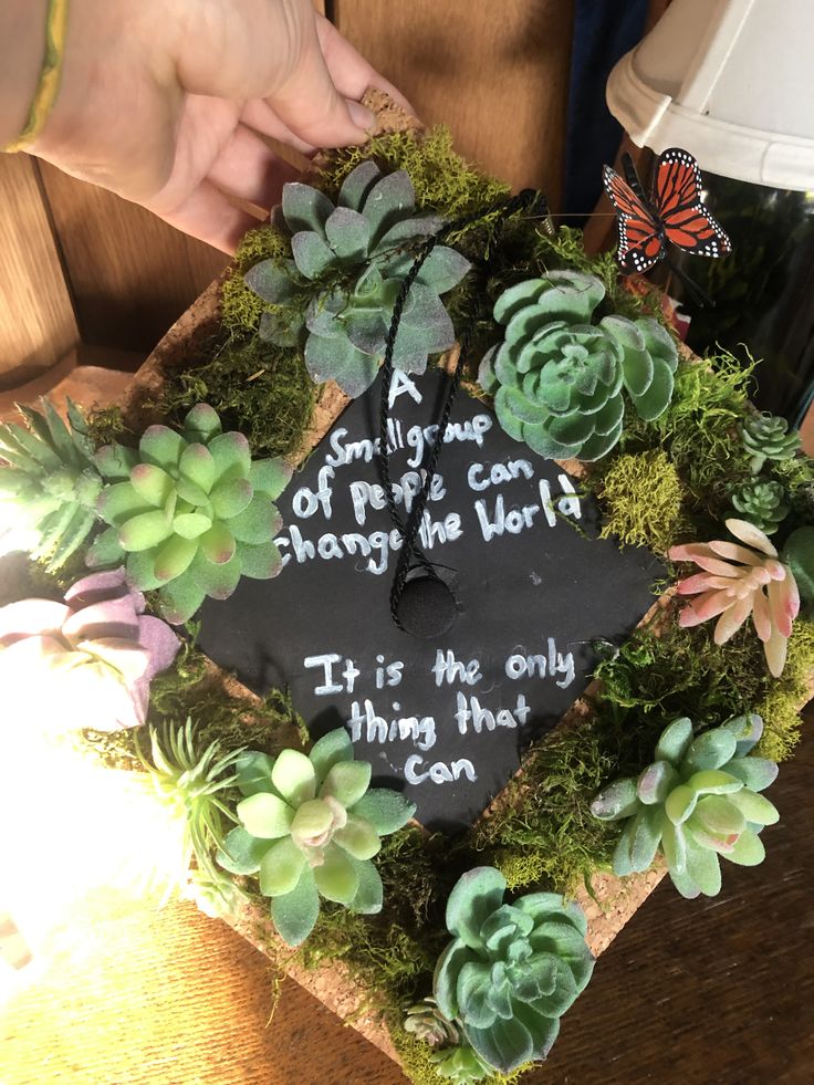 a graduation cap with succulents and writing on it is surrounded by greenery