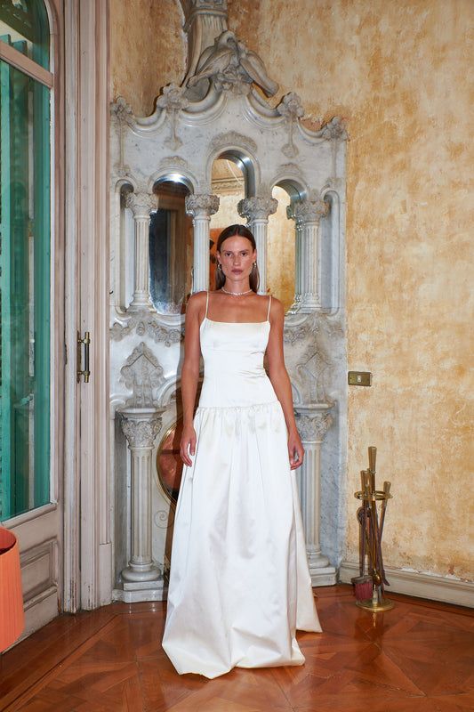 a woman in a white wedding dress standing in front of an ornate doorway and looking at the camera