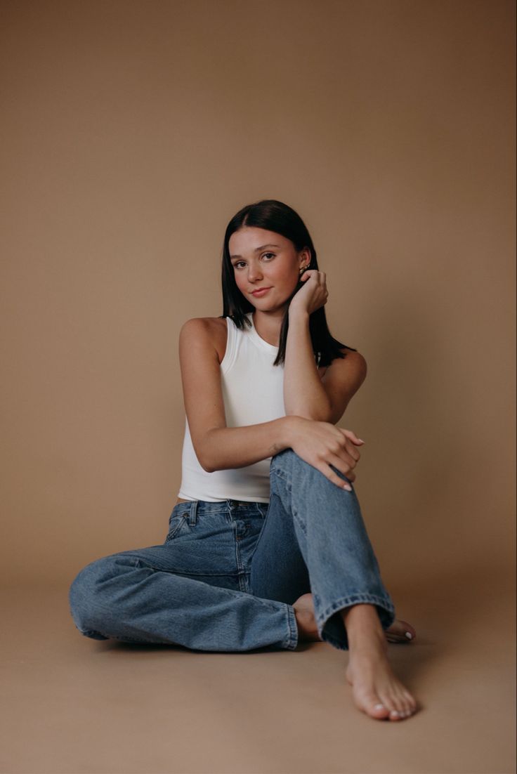 a woman is sitting on the floor with her legs crossed and she is wearing jeans