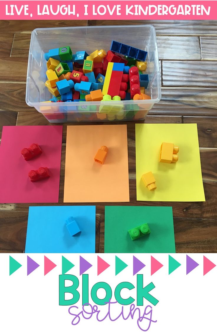 a plastic container filled with lego blocks sitting on top of a wooden floor next to colored paper