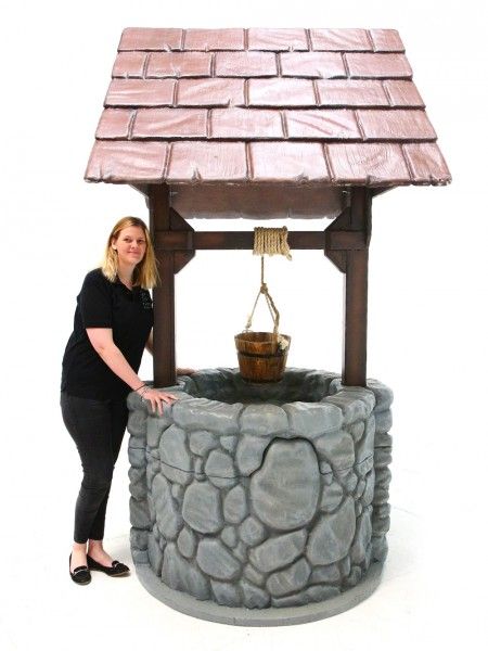 a woman standing next to a stone fountain with a water feature on it's side