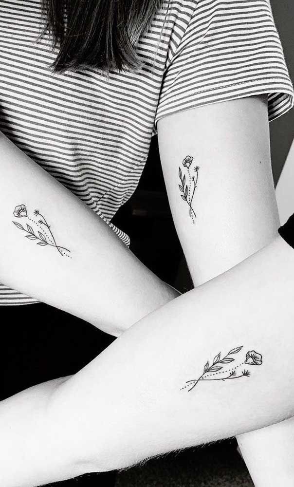 two women with matching tattoos on their arms, one is holding the other's arm