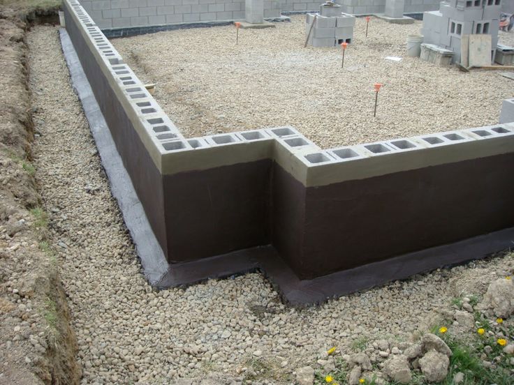 an unfinished concrete wall in the middle of a construction area with rocks and gravel around it