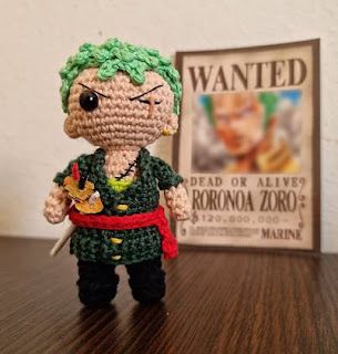 a crocheted doll is sitting on a table next to a wanted poster,