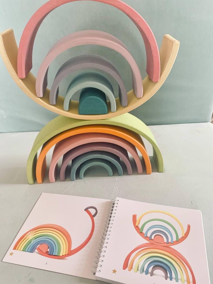 a stack of colorful spiral notebooks sitting on top of a table next to an open book