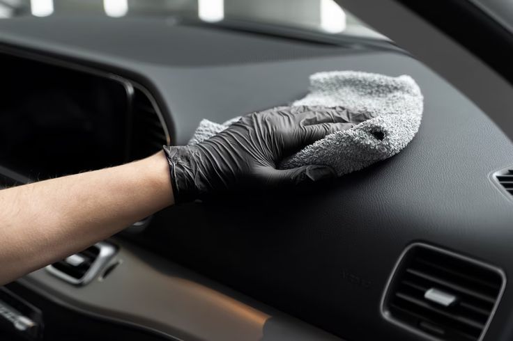 a person cleaning the inside of a car with a microfiber cloth and glove