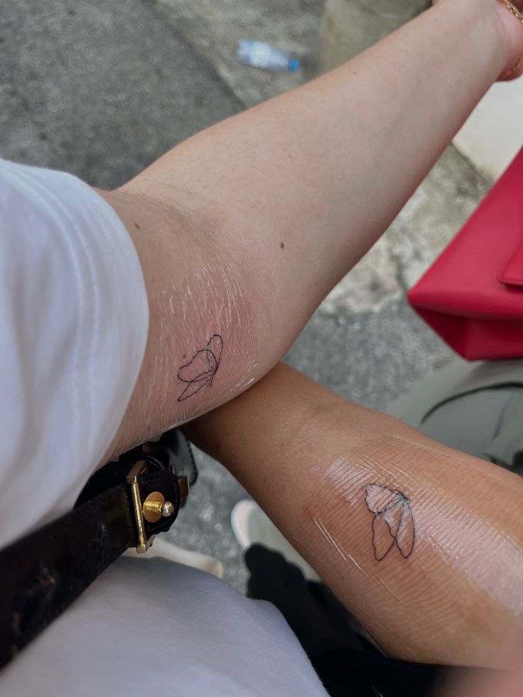 two people with small tattoos on their arms and legs, one is holding the other's arm