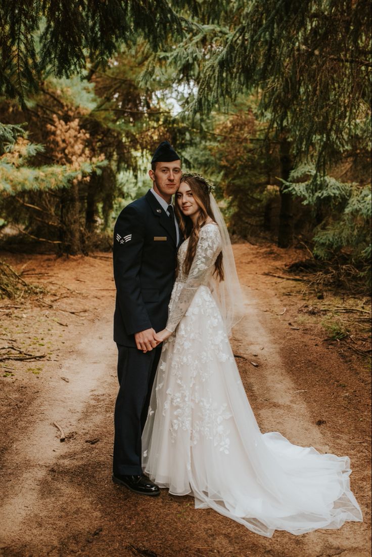 a bride and groom posing for a photo in the woods