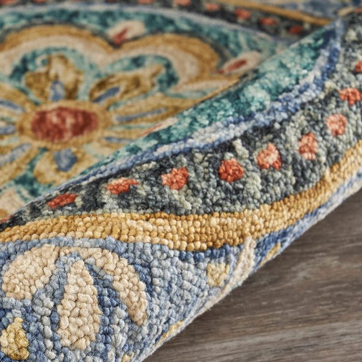 an area rug on top of a wooden floor with a blue and yellow design in the middle