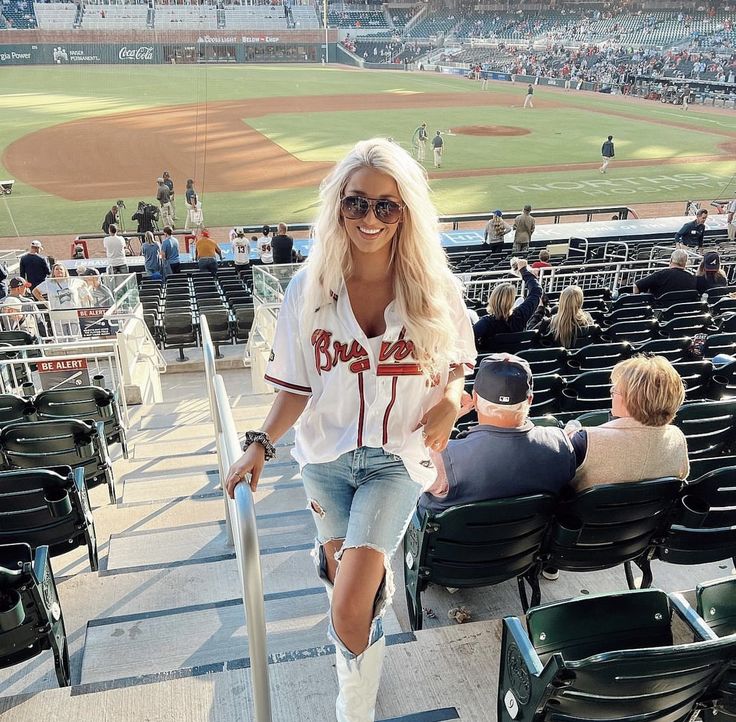 a woman walking up the stairs at a baseball game