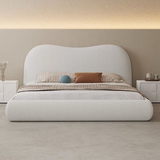 a large white bed sitting in a bedroom on top of a hard wood floor