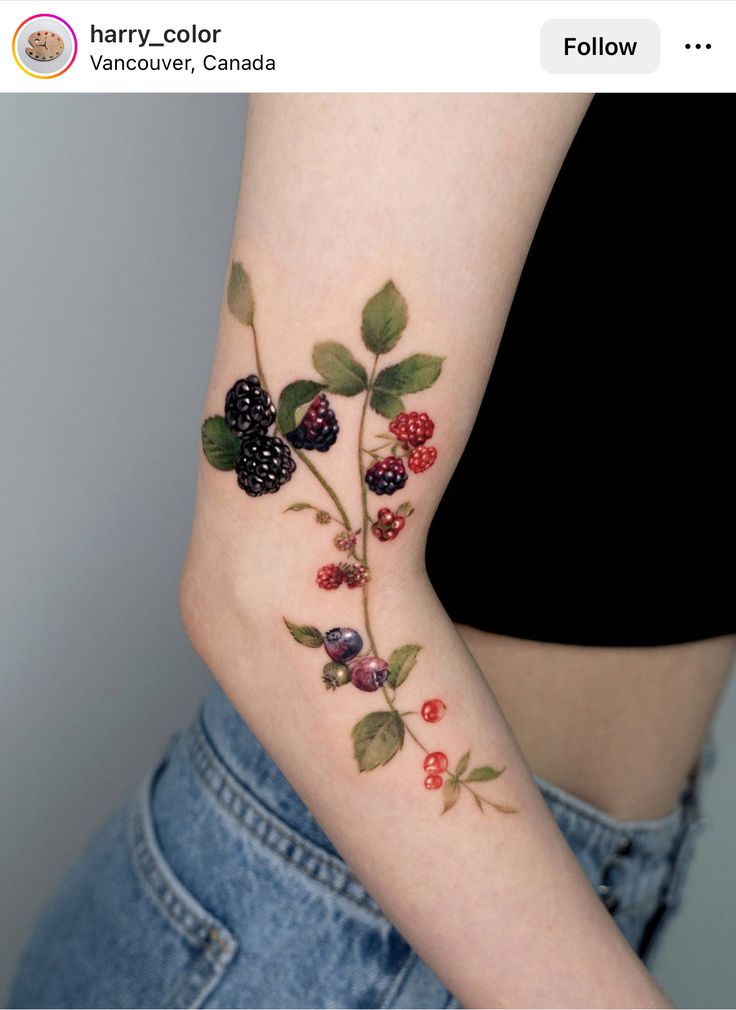 a woman's arm with berries and leaves on it