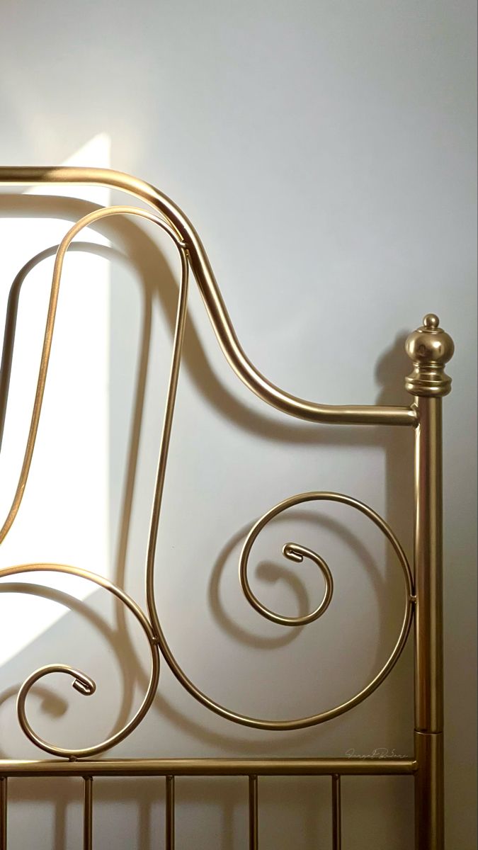 a gold metal bed frame against a white wall