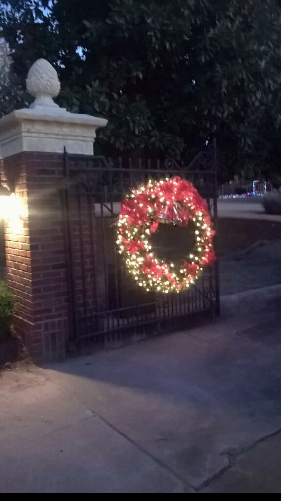 a christmas wreath is hanging on a gate