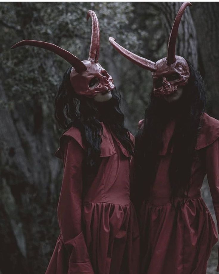 two women in red dresses with horns on their heads are standing next to each other