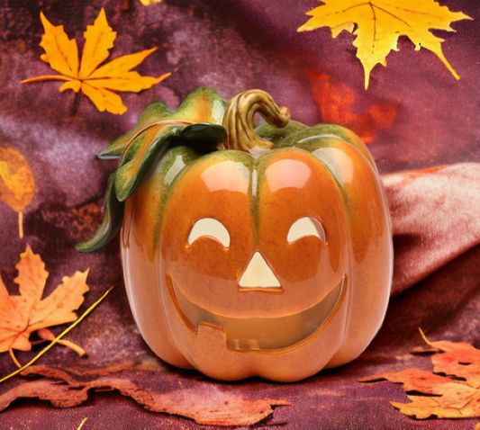 a carved pumpkin sitting on top of a purple cloth with leaves around it's sides