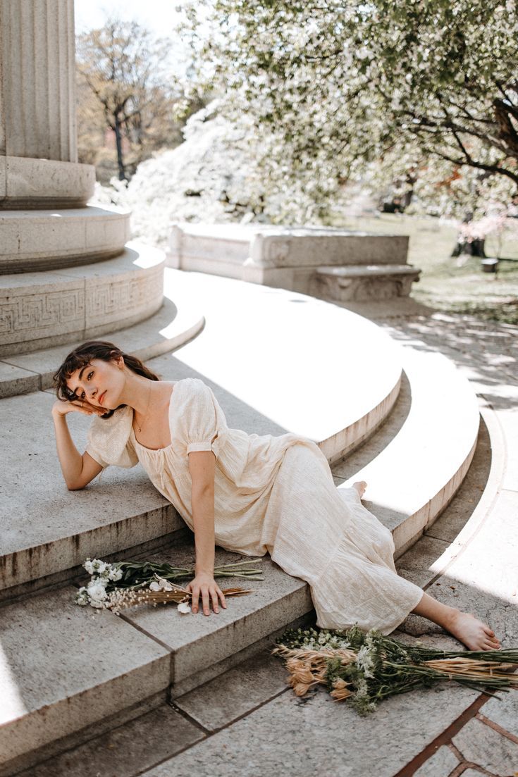 a woman laying on steps with flowers in her hand