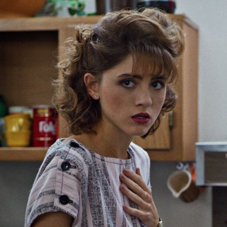 a woman is standing in the kitchen with her hand on her chest