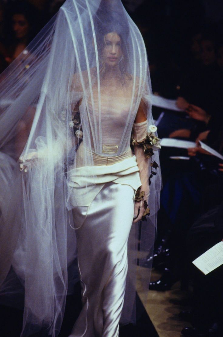 a woman walking down a runway with a veil over her head