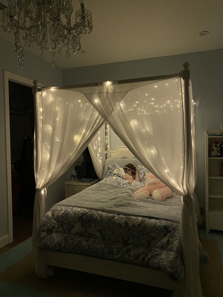 a woman laying in bed under a canopy with lights on the ceiling and curtains over her head