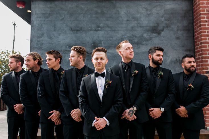 a group of men standing next to each other wearing black tuxedos and bow ties