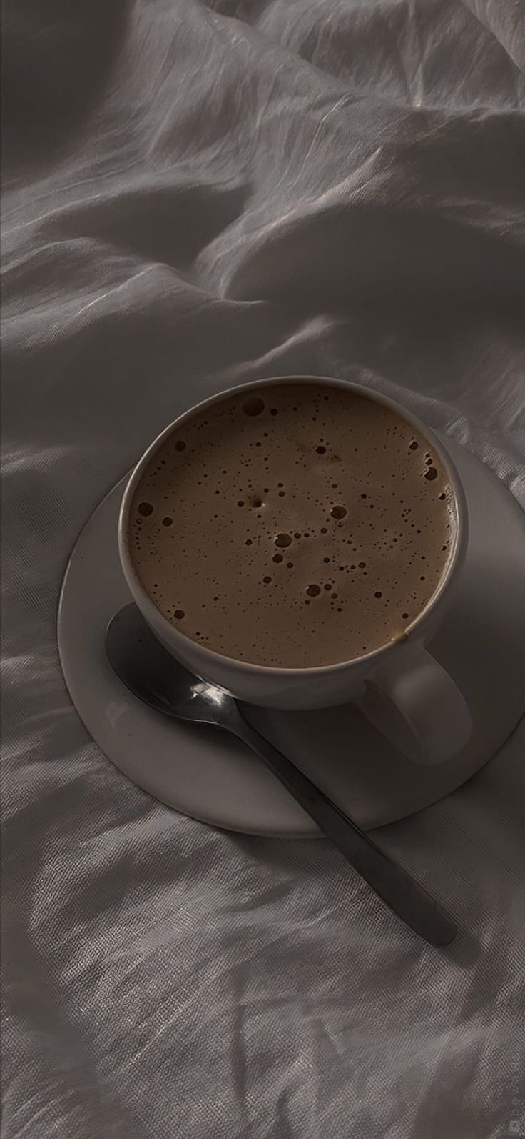 a cup of hot chocolate on a saucer with a spoon resting on the plate