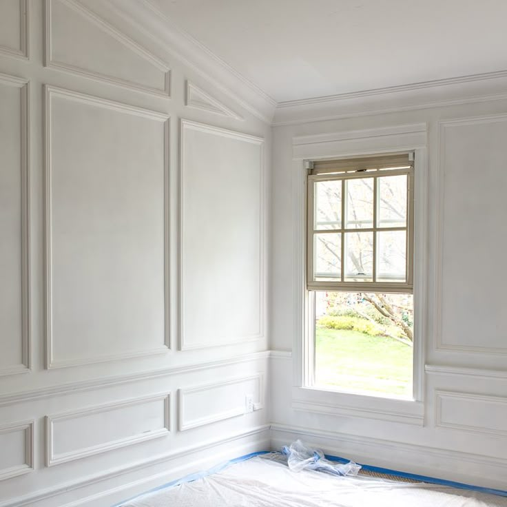 an empty room with white paint on the walls and blue tape taped to the floor