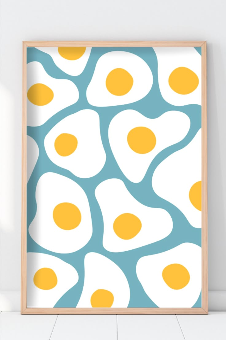 an egg print is hanging on the wall in front of a white background with blue and yellow eggs