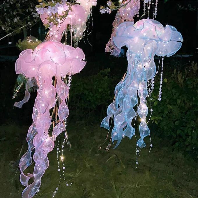 pink and blue jellyfish lanterns at night, hanging from a pink flowering tree Lantern Fairy Lights, Diy Jellyfish Decoration, Jellyfish Lights, Jellyfish Haircut, Jellyfish Tentacles, Pirate Halloween Party, Hanging Jellyfish, Jellyfish Lantern, Diy Jellyfish