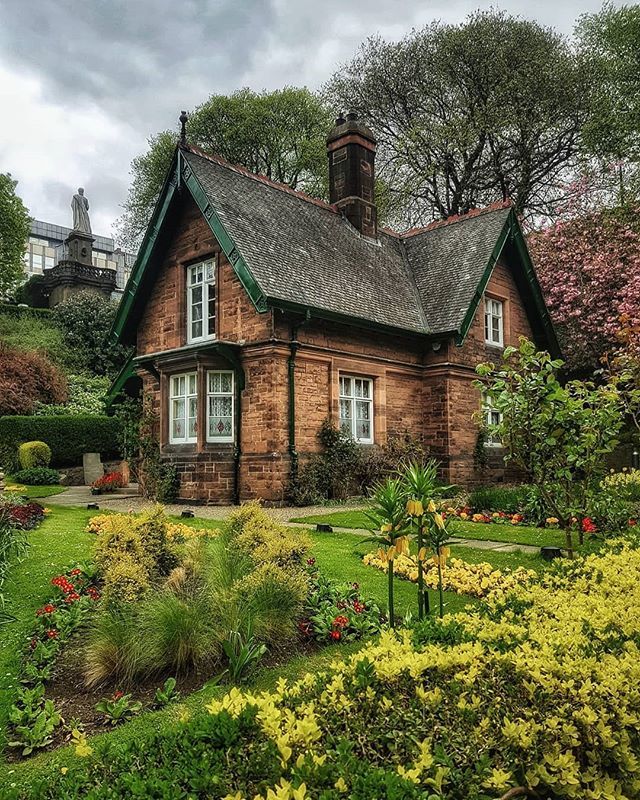 a red brick house surrounded by lush green grass and flowers in the front yard,