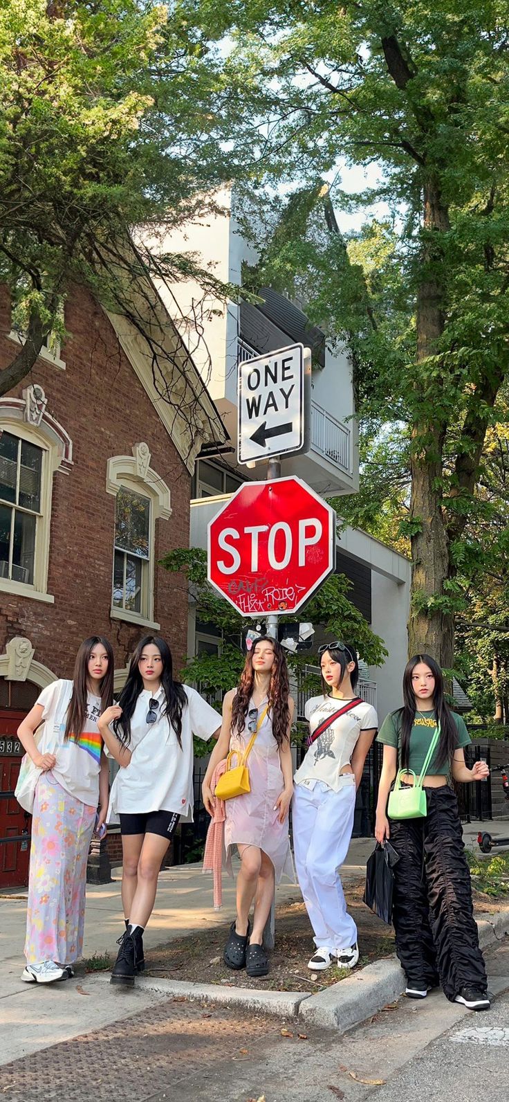 group of young women standing on the sidewalk under a stop sign