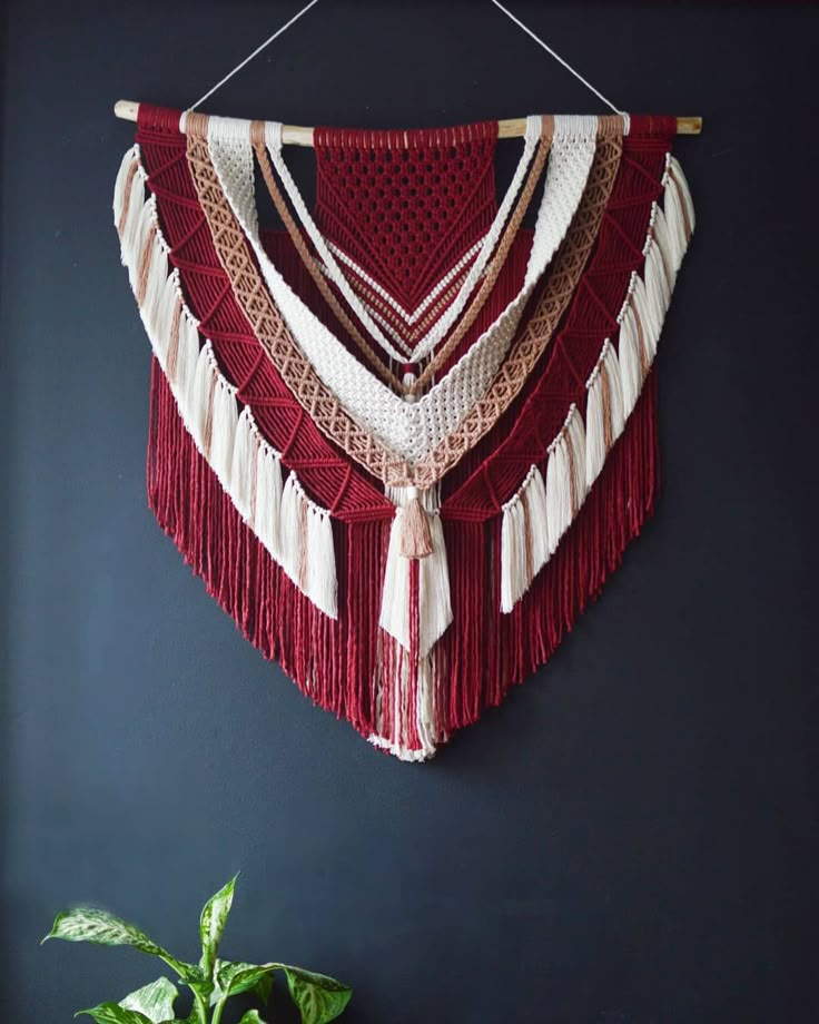 a red and white wall hanging next to a potted plant