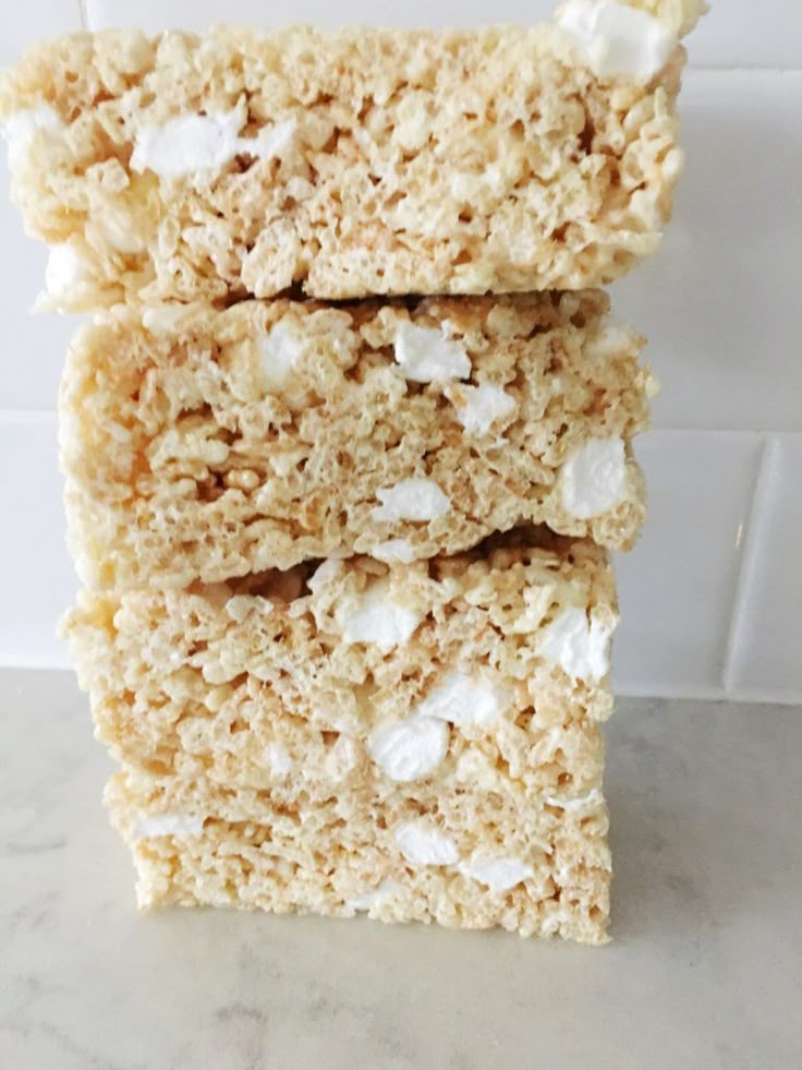 three pieces of rice krispy treats stacked on top of each other in front of a white tile wall