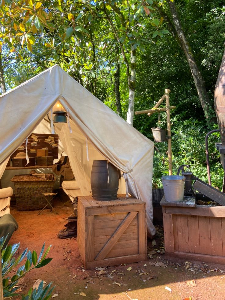 a tent is set up in the woods with potted plants and pots on it