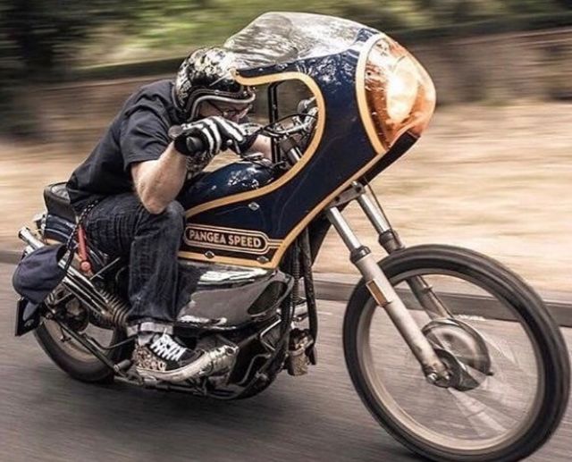 a man riding on the back of a motorcycle down a street