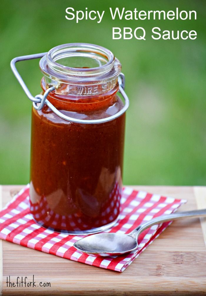 a jar filled with bbq sauce sitting on top of a red and white checkered napkin