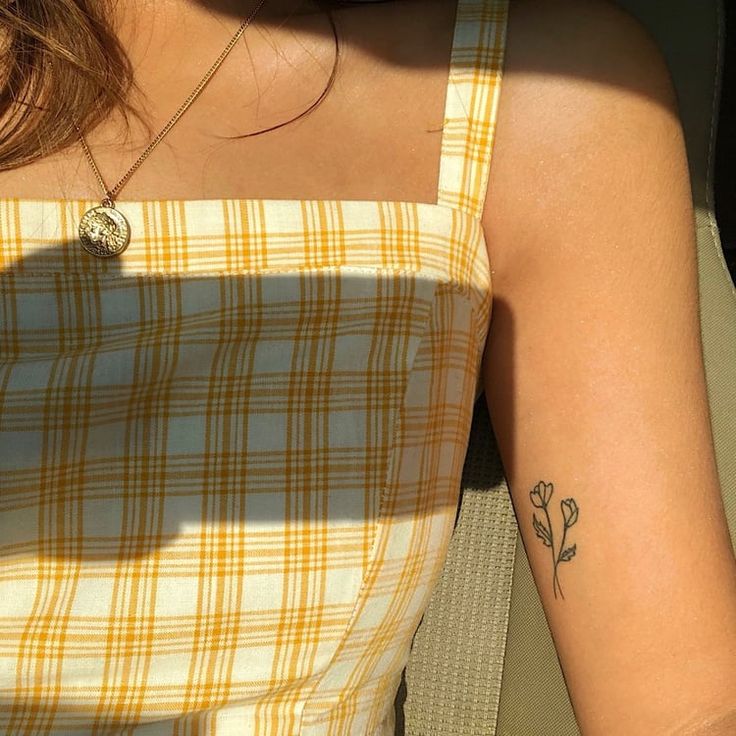 a woman with a small flower tattoo on her left arm and right arm behind her back