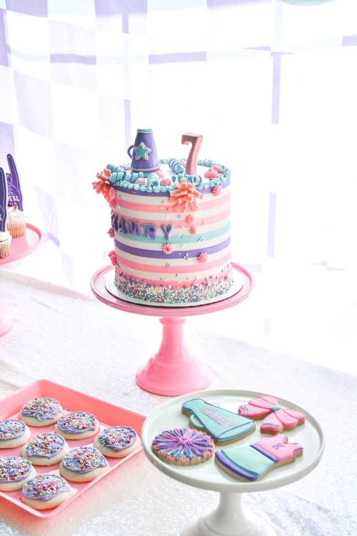 there is a birthday cake and cupcakes on the table next to each other