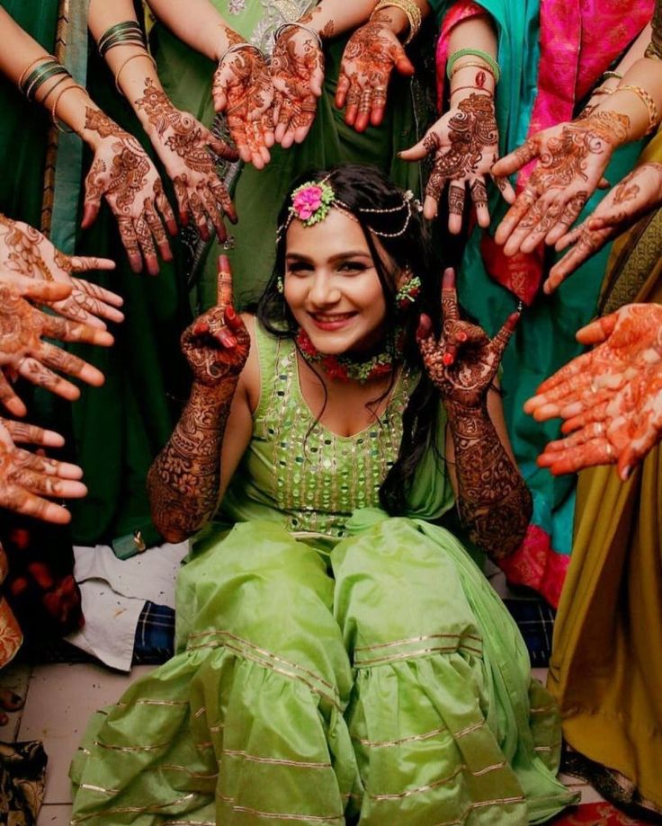 a woman sitting on the ground surrounded by hands covered in hendikes and mudi