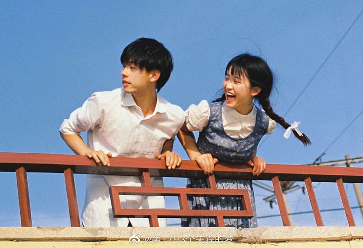 two people standing next to each other on a wooden balcony over looking the city with power lines in the background