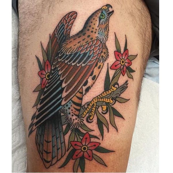 a tattoo on the leg of a man with an eagle and flowers in it's claws