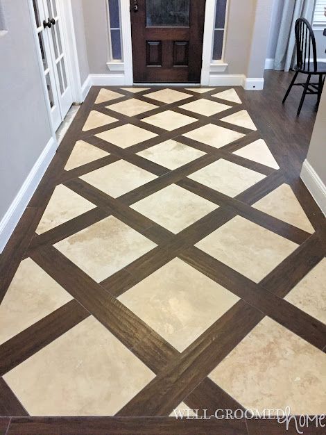 an entryway with white and brown tile on the floor next to a wooden door