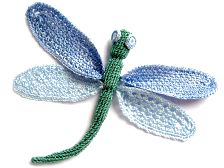 a crocheted dragonfly sitting on top of a white surface