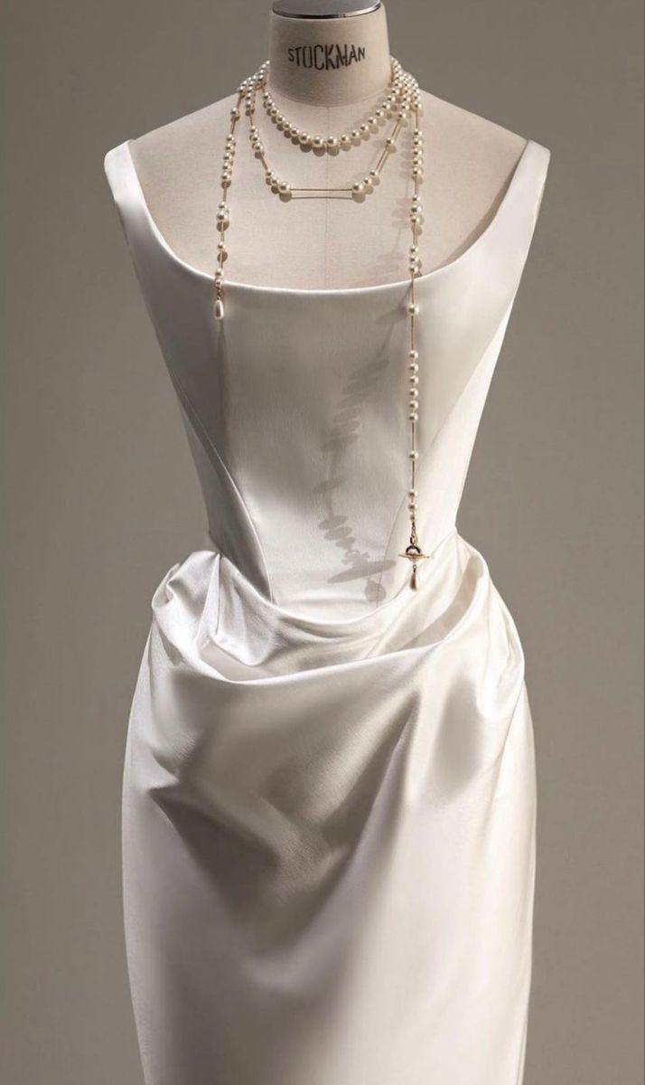 a mannequin with a white dress on it's head and pearls around the neck